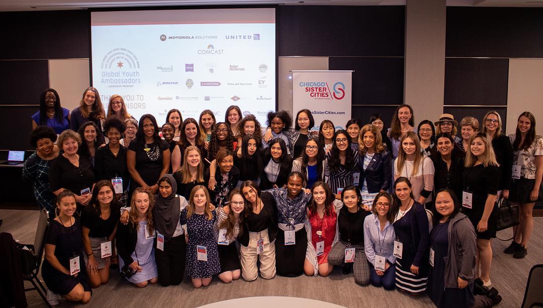 A large group of girls and their mentors, from around the world and Chicago, pose together at a mentorship luncheon.