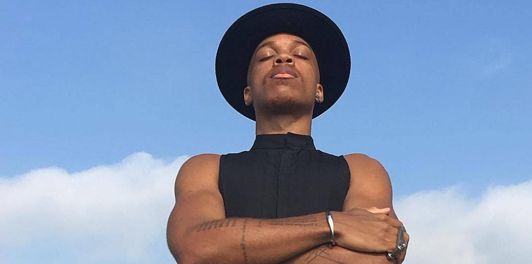 Vernon Francois with crossed hands and eyes closed in front of a clear sky backdrop.