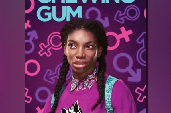 A young Black woman with two braids, wearing a pink sweater with a zebra on the front, makes an awkward face toward something off-camera.