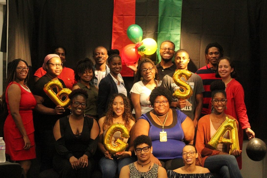 A group of Black Graduate Student Association members holds balloons of the letters 