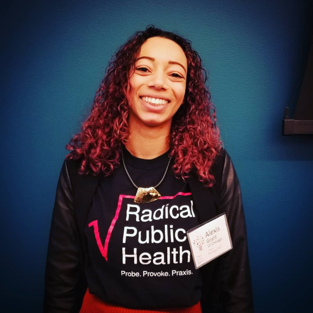 Alexis Grant, wearing a Radical Pubic Health shirt, smiling toward the camera