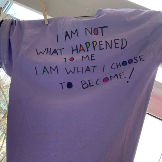 Black text on a purple t-shirt reads, “I am not what happened to me, I am what I choose to become!”